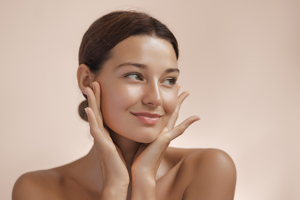 Happy beautiful young adult woman showing her perfect face with healthy shiny skin