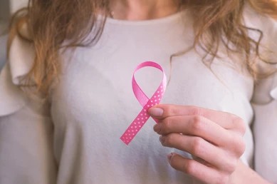 Woman holding a breast cancer ribbon considering breast reconstruction in Pittsburgh, PA