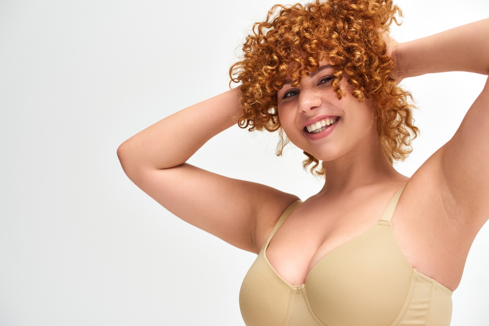 Woman in a bra smiling after breast reduction in Pittsburgh, PA