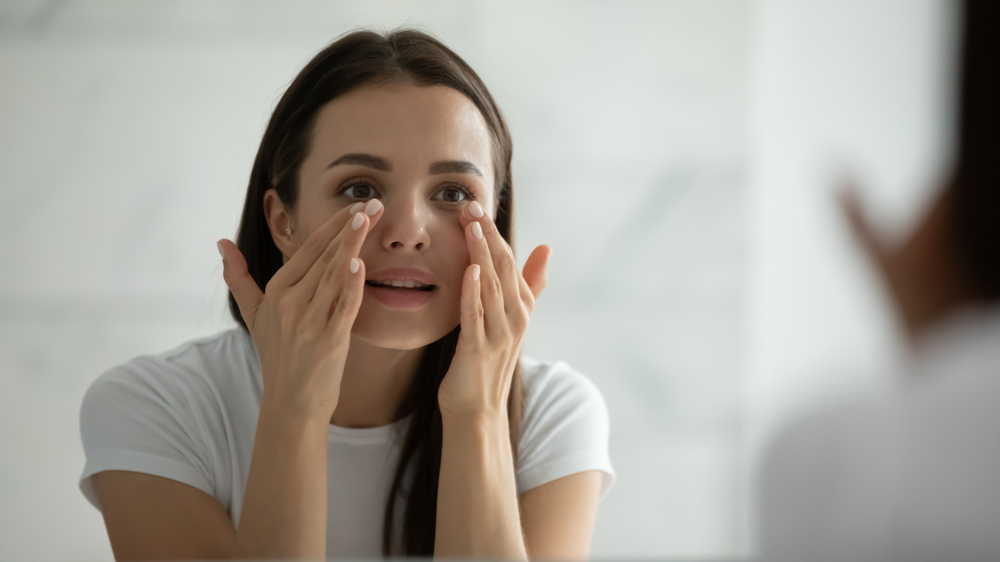 Woman looking in the mirror touching face wanting mini facelift in Pittsburgh, PA