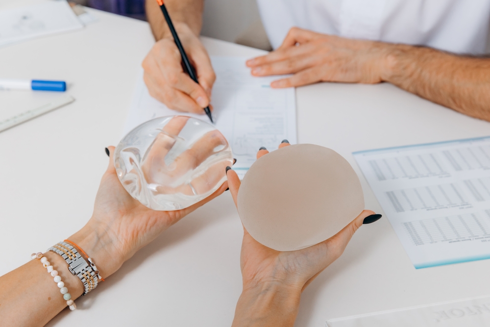 Woman holding two breast implants making decisions for revision breast augmentation in Pittsburgh
